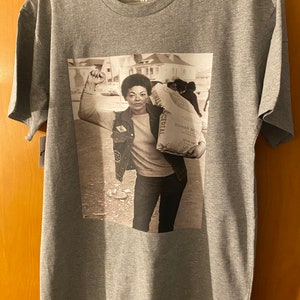 May include: A gray t-shirt with a black and white photo of a woman holding a bag of flour. The bag of flour has the text "Roman Meal" printed on it. The t-shirt has the text "K-Funk Co" printed on the tag.