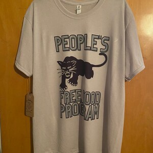 Pode incluir: Uma camiseta cinza claro com um gr&aacute;fico de pantera negra e o texto "PEOPLE'S FREE FOOD PROGRAM".