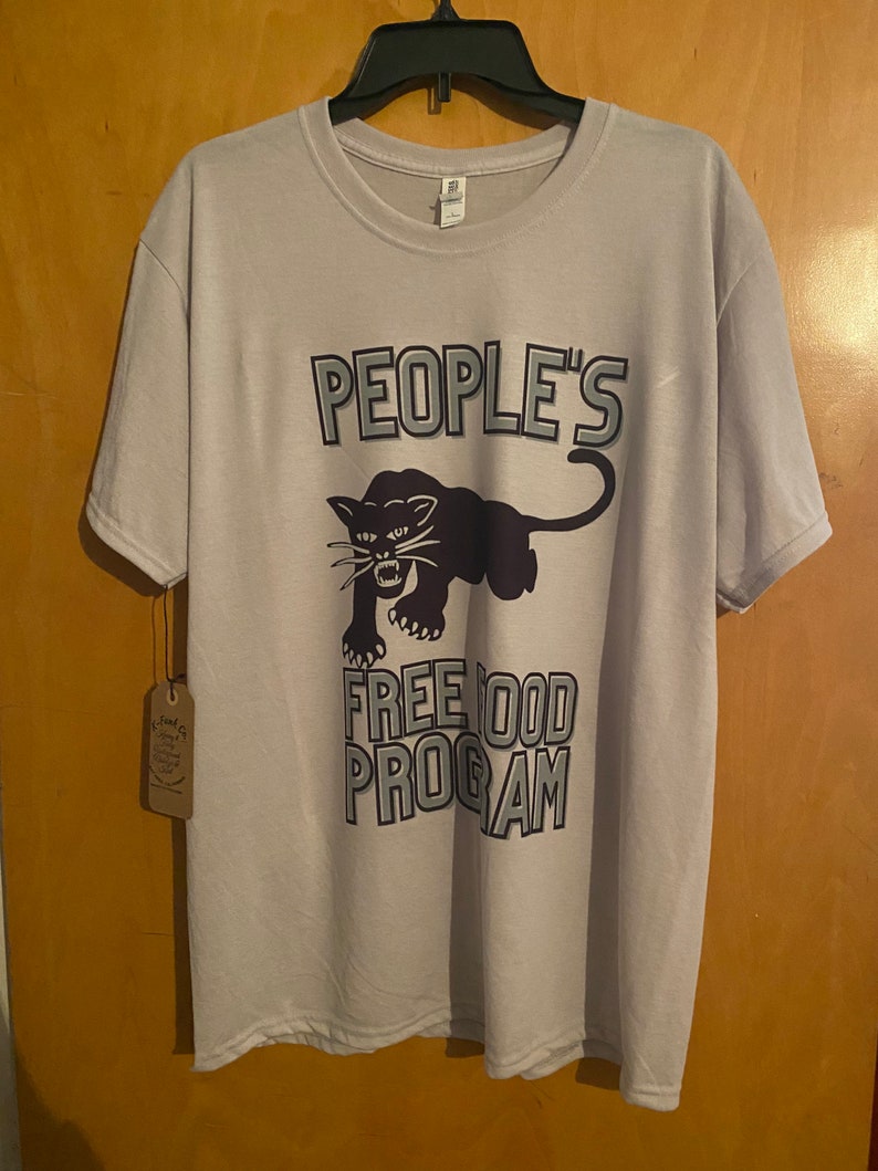 Pode incluir: Uma camiseta cinza claro com um gr&aacute;fico de pantera negra e o texto "PEOPLE'S FREE FOOD PROGRAM".