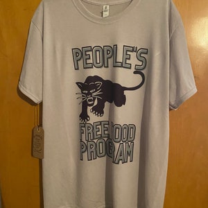 Pode incluir: Uma camiseta cinza claro com um gr&aacute;fico de pantera negra e o texto "PEOPLE'S FREE FOOD PROGRAM" em negrito com um contorno branco.