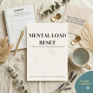 May include: A flat lay featuring a notebook, pen, and a book titled "Mental Load Reset." The book has a line drawing of a face and the text "7-Day System for Overwhelmed Mums." Other items include paperclips, a mug, and a card with inspirational text.