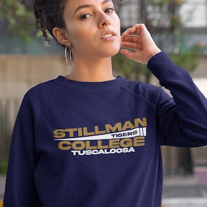 May include: A navy blue sweatshirt with a gold and white graphic that reads "Stillman College Tigers Tuscaloosa".