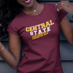 May include: A maroon t-shirt with the text "CENTRAL STATE alumna" in white and gold lettering.
