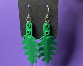 May include: A pair of green leaf-shaped earrings made from Lego bricks. The earrings are hanging from silver hooks.