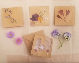 Peut inclure: Quatre cartes brunes avec des fleurs et des feuilles pressées. Les cartes sont vierges et prêtes à être écrites. Les fleurs sont de couleur violette, blanche et rose.
