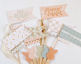 May include: A set of six pastel bunny cupcake toppers with a variety of Easter-themed flags. The flags feature checkered patterns, floral designs, and the phrases "He is Risen", "Hoppy Easter", and "Happy Easter".