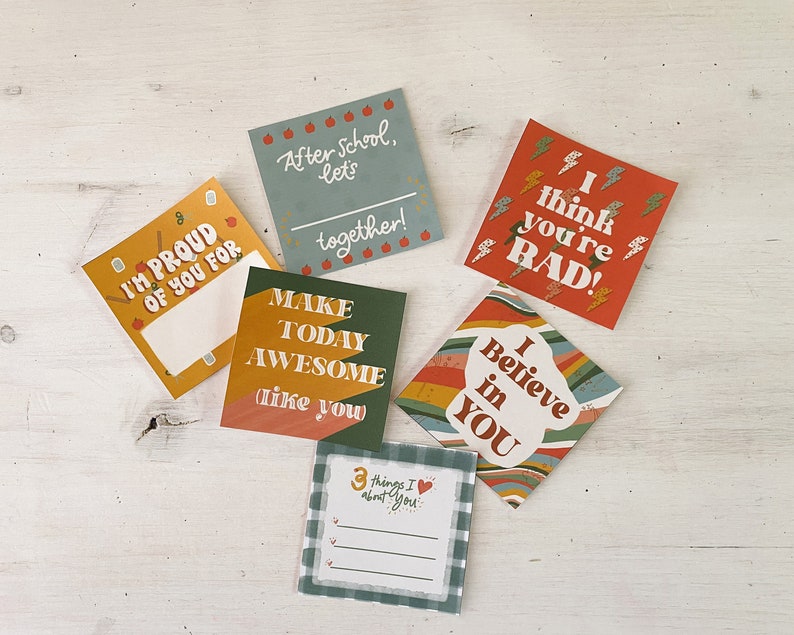 Op de afbeelding: Een verzameling kleurrijke vierkante kaarten met verschillende berichten. E&eacute;n kaart leest "I'M PROUD OF YOU FOR" met ruimte om te schrijven. Andere kaarten zeggen "After school, let's together!", "I think you're RAD!", "Make today awesome like you", "I Believe in YOU" en "3 things I about you".