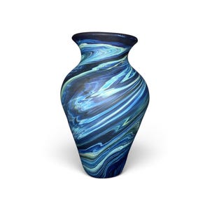 May include: A glass vase featuring a swirling marbled pattern of deep navy blue, bright cyan, and soft white tones. The vessel has a wide, rounded body that tapers toward a narrow base and flares slightly at the top opening with a smooth finish.