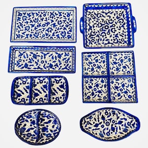 Puede incluir: Un juego de siete platos para servir de cerámica azul y blanca con motivos florales. El juego incluye un plato rectangular grande, un plato rectangular más pequeño, un plato cuadrado con cuatro compartimentos, un plato rectangular con tres compartimentos, un plato redondo con dos compartimentos y dos platos ovalados.