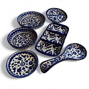 Könnte beinhalten: Ein Set aus sechs blauen und weißen Keramik-Servierplatten mit Blumenmustern. Das Set enthält eine große rechteckige Platte, vier kleine runde Platten und einen Servierlöffel.