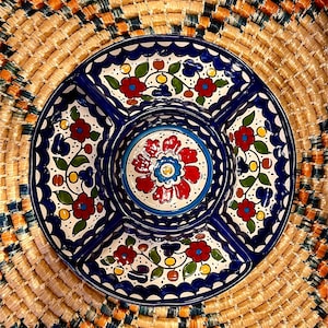 May include: A blue and white ceramic serving dish with four sections and a central bowl. The dish is decorated with colorful floral patterns in red, green, yellow, and blue.