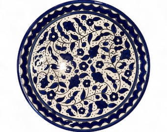 Könnte beinhalten: Runder Keramikteller mit weißem Hintergrund und blauem Blumenmuster. Der Teller hat einen gewellten blauen Rand und ein detailliertes Muster aus blauen Blumen und Blättern. Ein dekoratives Objekt.