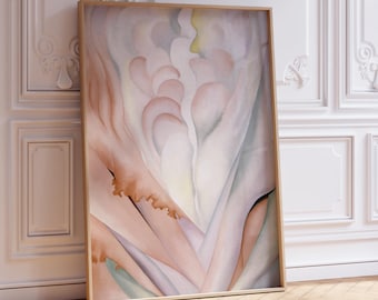 May include: A framed abstract art print featuring soft pastel colors of pink, peach, and cream. The artwork leans against a white wall with ornate molding, set on a wooden floor. The piece has a light brown wooden frame.