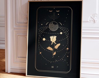 May include: A black and gold tarot card with the number III and a white rose with a stem and leaves. The rose is surrounded by a circle of gold dots and a crescent moon with a face. The card has a black background and gold accents.