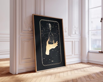 Puede incluir: Una impresión de arte mural rectangular vertical enmarcada con fondo negro y líneas doradas. La ilustración muestra una mano sosteniendo un cristal con una pluma encima, rodeada por un borde dorado fino y el número romano VIII.