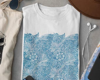 Może przedstawiać: Biały t-shirt z niebieskim nadrukiem botanicznym na dolnej połowie, w towarzystwie brązowego kapelusza, okularów przeciwsłonecznych, płóciennej torby, czarnego notatnika z niebieskim długopisem, aparatu w stylu vintage, białych słuchawek przewodowych i złożonej mapy.