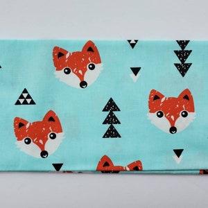 May include: A turquoise fabric with a repeating pattern of red foxes, black trees, and white triangles.