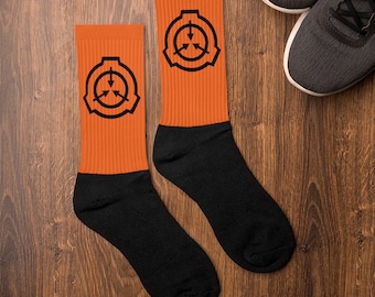 SCP財団のロゴがオレンジ地に黒で入ったソックス。SCPファンや快適なソックスとして最適なギフトです。