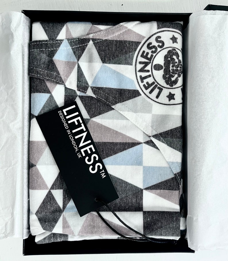 May include: A black and white geometric patterned fabric with a blue and gray geometric pattern. The fabric is in a black box with a black tag that says "Liftness TM Designed in London, UK".