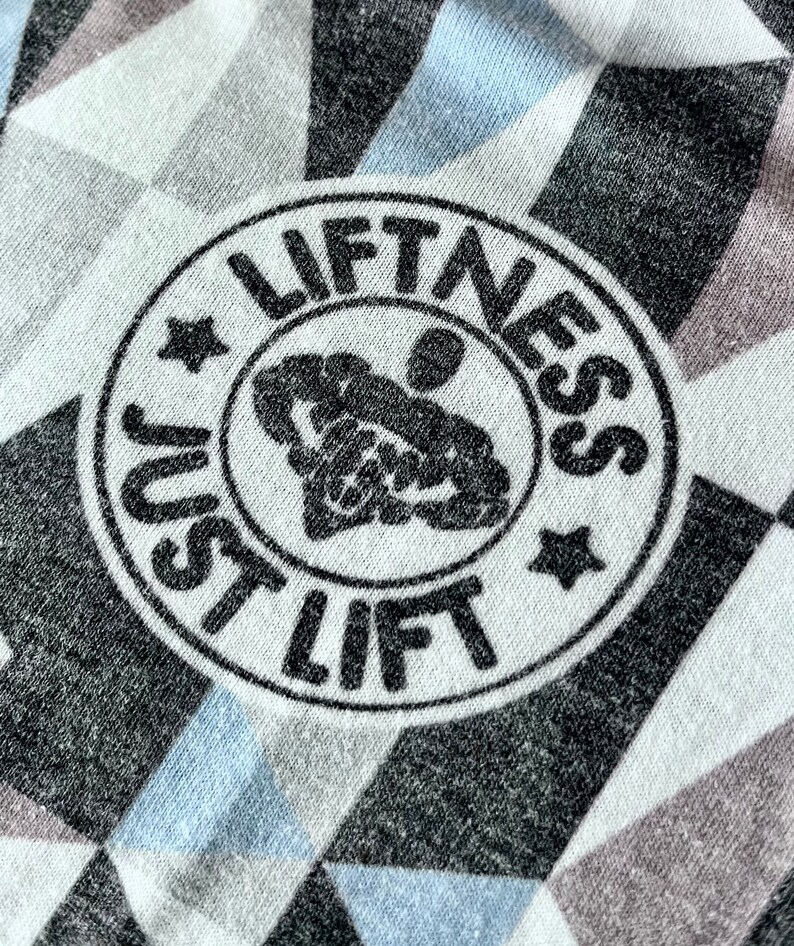 May include: A white and gray patterned fabric with a black circle containing the text "Just Lift Fitness" and a stylized image of a person lifting weights.
