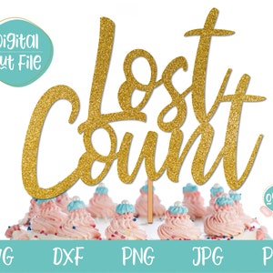 May include: Gold glitter cake topper with the words "Lost Count" in a cursive font. The topper is sitting on a cake with pink and blue frosting.