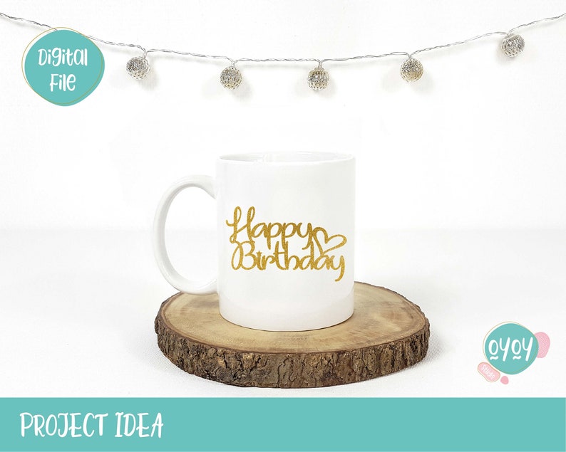 Op de afbeelding: Een witte keramische mok met een gouden glitterontwerp met de tekst "Happy Birthday" met een hartje. De mok staat op een houten schijf.