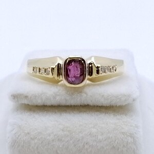 Könnte beinhalten: Ein goldener Ring mit einem rosafarbenen Edelstein und kleinen Diamanten, die in die Band gefasst sind.