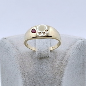 Könnte beinhalten: Ein goldener Ring mit einem roten Herzen und drei kleinen weißen Steinen, die in einem Pfotenabdruck-Design eingefasst sind.