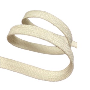 Pu&ograve; includere: Un cordoncino di cotone beige, visto da vicino, che mostra la trama del tessuto. Il cordoncino &egrave; avvolto a spirale sciolta.