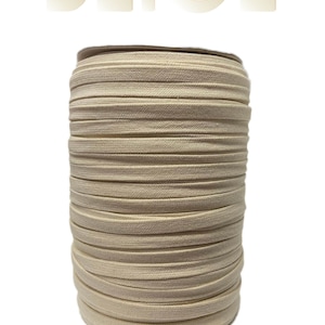 Pu&ograve; includere: Un rotolo di cordoncino elastico in cotone beige. Il cordoncino &egrave; avvolto strettamente su un rotolo di cartone.