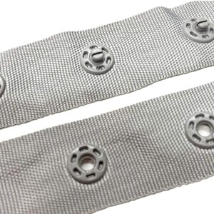 May include: Grey fabric tape with silver metal eyelets. The tape is designed for use with curtains or other home decor projects.