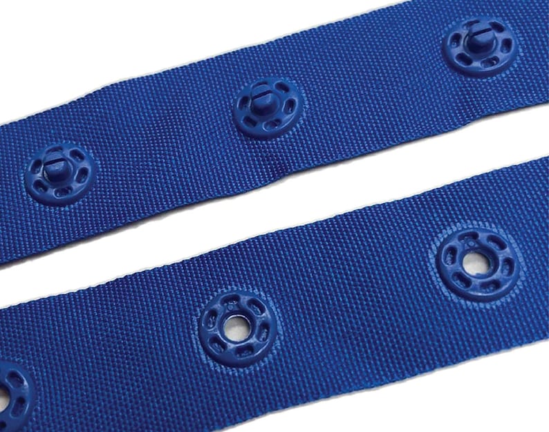 May include: Blue webbing with plastic snap fasteners. The webbing is a woven fabric with a textured surface. The fasteners are round with a small screw in the centre.
