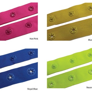 May include: Four different colors of elastic webbing with snap buttons. The colors are hot pink, mustard yellow, royal blue, and neon green.
