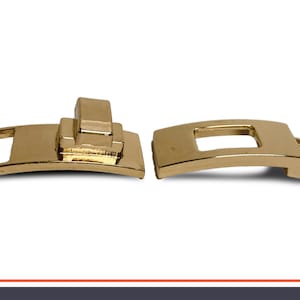 May include: Two gold metal slider buckles. The buckle on the left has a rectangular opening and a small, raised, rectangular piece on top. The buckle on the right has a rectangular opening.