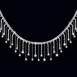 May include: A silver rhinestone necklace with dangling strands of rhinestones. The necklace is on a black background.