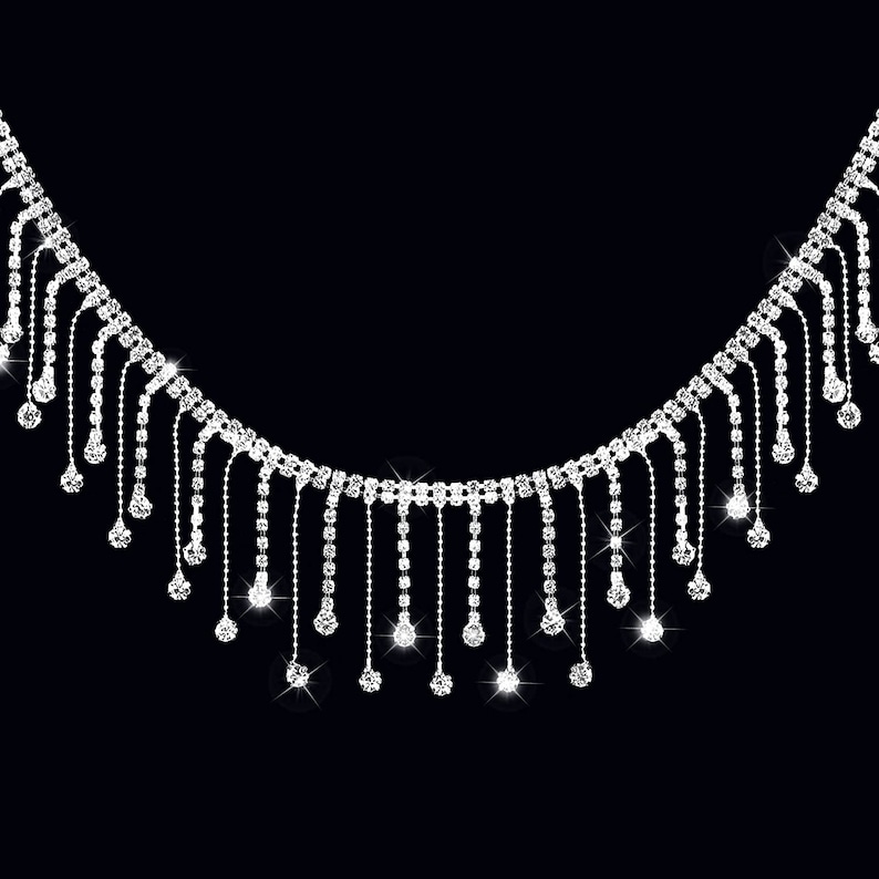 May include: A silver rhinestone necklace with dangling strands of rhinestones. The necklace is on a black background.