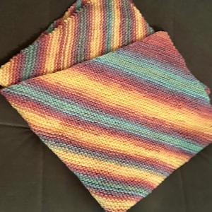 Könnte beinhalten: Zwei gestrickte Geschirrtücher mit diagonalem Streifenmuster. Die Farben umfassen Gelb-, Orange-, Türkis-, Lila- und Rosatöne. Die Geschirrtücher sind gefaltet und übereinander gelegt, wodurch ein strukturiertes Aussehen entsteht.