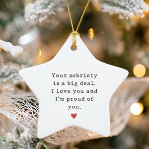 K&ouml;nnte beinhalten: Wei&szlig;er, sternf&ouml;rmiger Anh&auml;nger aus Keramik mit einem roten Herzen und dem Text "Your sobriety is a big deal. I love you and I'm proud of you."