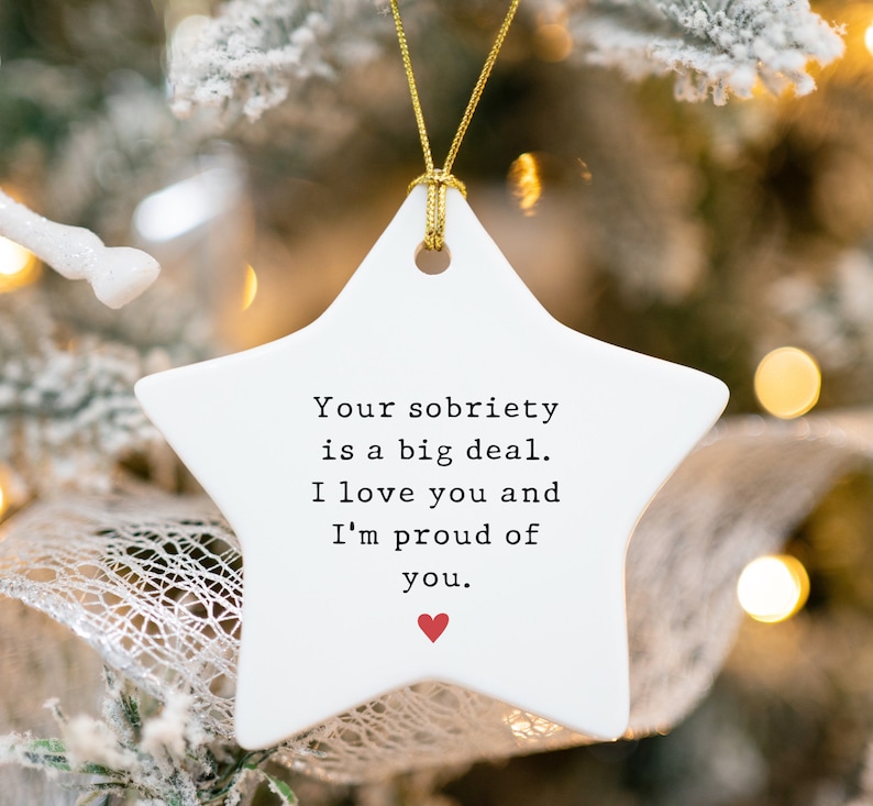 K&ouml;nnte beinhalten: Wei&szlig;er, sternf&ouml;rmiger Anh&auml;nger aus Keramik mit einem roten Herzen und dem Text "Your sobriety is a big deal. I love you and I'm proud of you."
