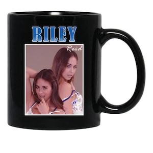 May include: Black ceramic mug featuring a photograph of two women. The mug has the name "RILEY" in blue text at the top, with "Reid" below. The mug's handle is on the right side.