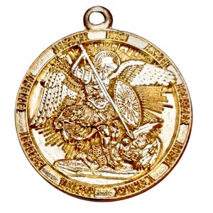 May include: Gold-colored pendant featuring a detailed relief of Saint Michael the Archangel. The saint is depicted with a sword and shield, standing over a defeated figure. The pendant has a circular shape with an attached loop for a chain.