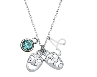 May include: Silver necklace with a blue crystal charm, a letter 'A' charm, and two silver charms shaped like theater masks, one smiling and one frowning.