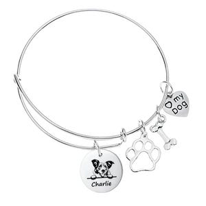 May include: Silver-toned bangle bracelet with multiple charms. Charms include a heart with "my Dog" text, a dog bone, a paw print, and a round charm with a dog illustration and the name "Charlie".