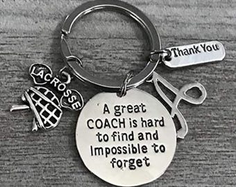 May include: Silver keychain with a lacrosse stick charm, a charm that says "A great COACH is hard to find and impossible to forget", and a charm that says "Thank You".