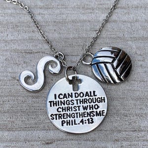 May include: Silver-toned necklace with three charms: a stylized letter "S", a volleyball, and a round pendant with a cross and the text "I CAN DO ALL THINGS THROUGH CHRIST WHO STRENGTHENS ME PHIL.4:13".