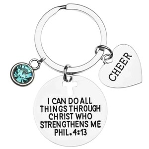 May include: Silver keychain with a round charm that says "I can do all things through Christ who strengthens me Phil. 4:13" and a heart charm that says "Cheer".