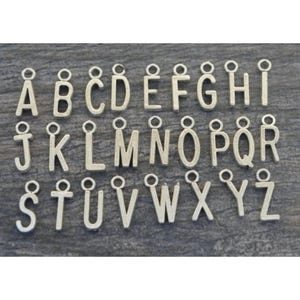 May include: Silver alphabet letter charms with a loop for attaching to jewelry or other crafts. The letters are arranged in alphabetical order from A to Z.