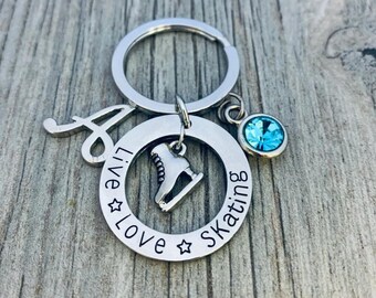 May include: Silver keychain with a charm of an ice skate, a blue crystal, and a silver circle with the text "Live Love Skating" engraved on it.