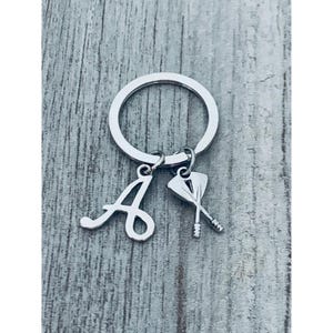 May include: Silver keychain with a letter A charm and a dart charm.