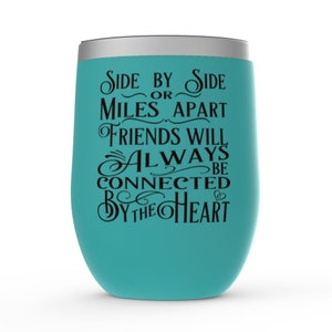 May include: Teal stainless steel wine tumbler with a black inscription that reads "Side by Side or Miles Apart Friends Will Always Be Connected By The Heart".